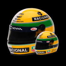 Load image into Gallery viewer, A collection of two mini Bell helmets, one full-sized and one miniature, both featuring Ayrton Senna branding and in yellow, green, and blue livery.